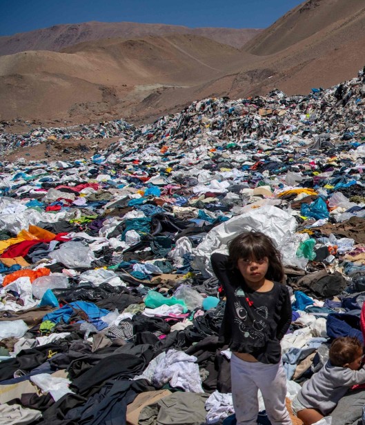 little girl standing in dumps of clothing